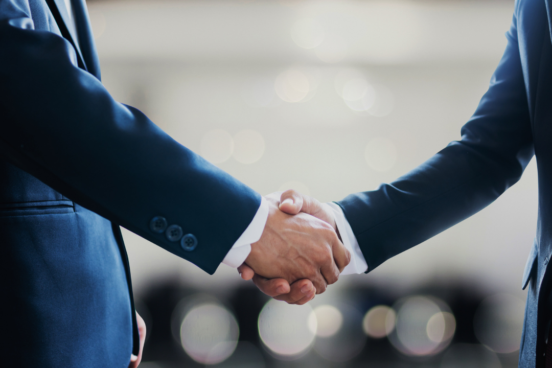 The foreground of two men formally shaking hands.